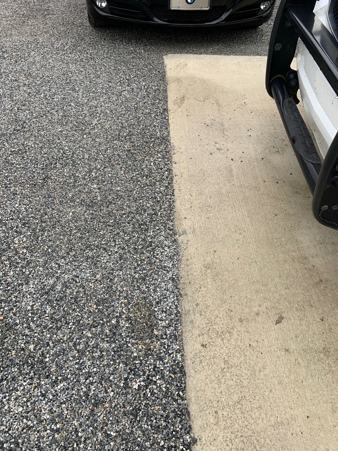 Chip and tar driveway surface meeting a concrete walkway