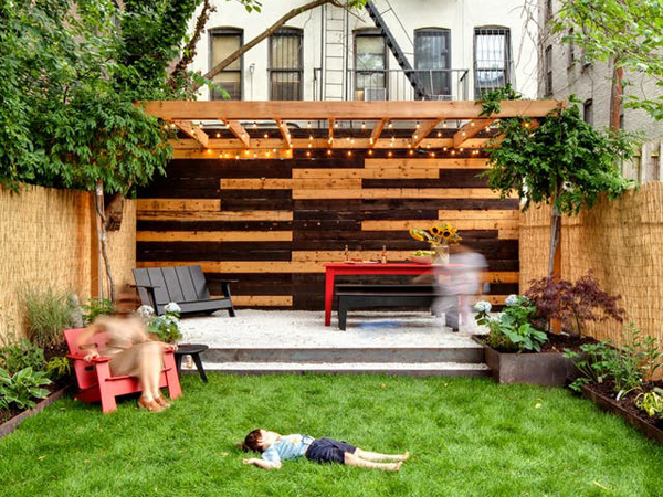 Cozy backyard with a wood deck and pergola, with lush green grass in the foreground and comfortable outdoor seating