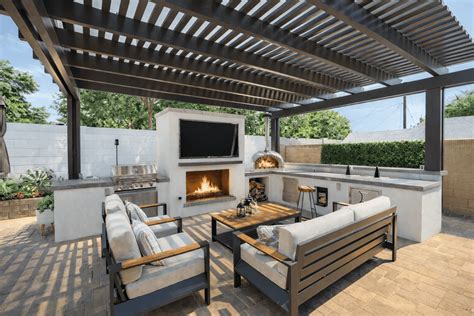 Modern pergola covering a relaxed seating area with a fireplace, outdoor kitchen, and pizza oven