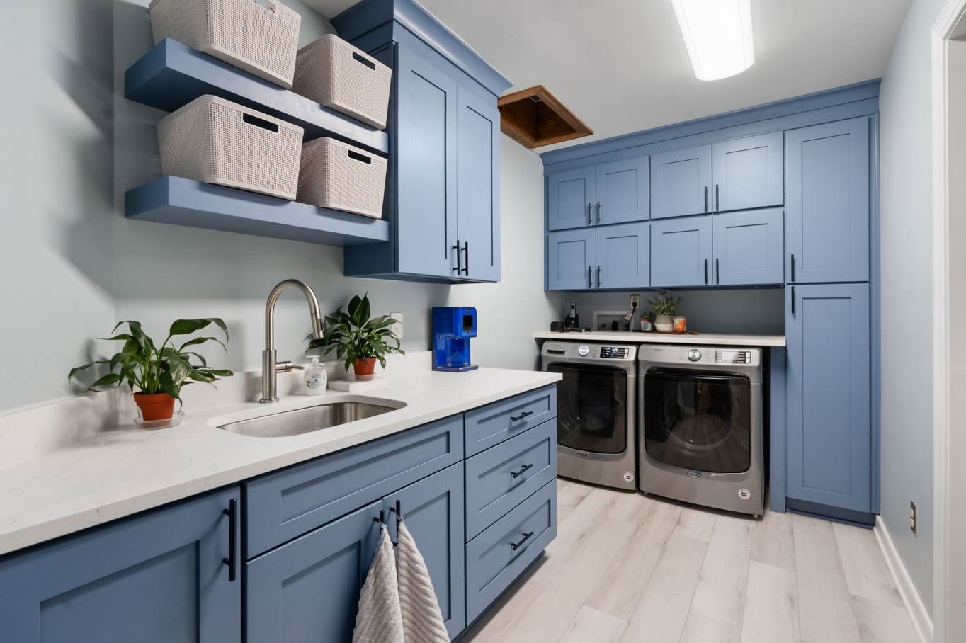 Thoughtfully designed blue laundry room with integrated storage, sink, and workspace