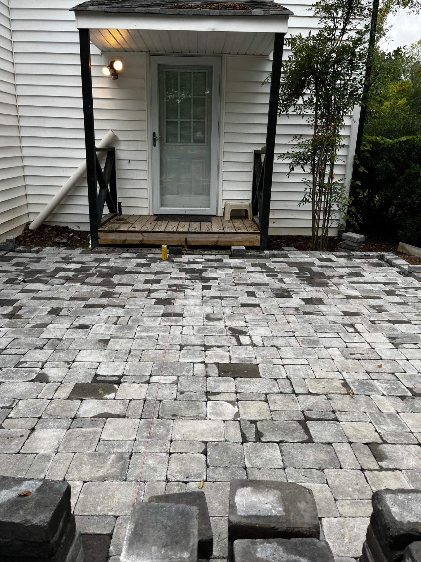 Cobblestone-style paver entry being laid at a covered side entrance