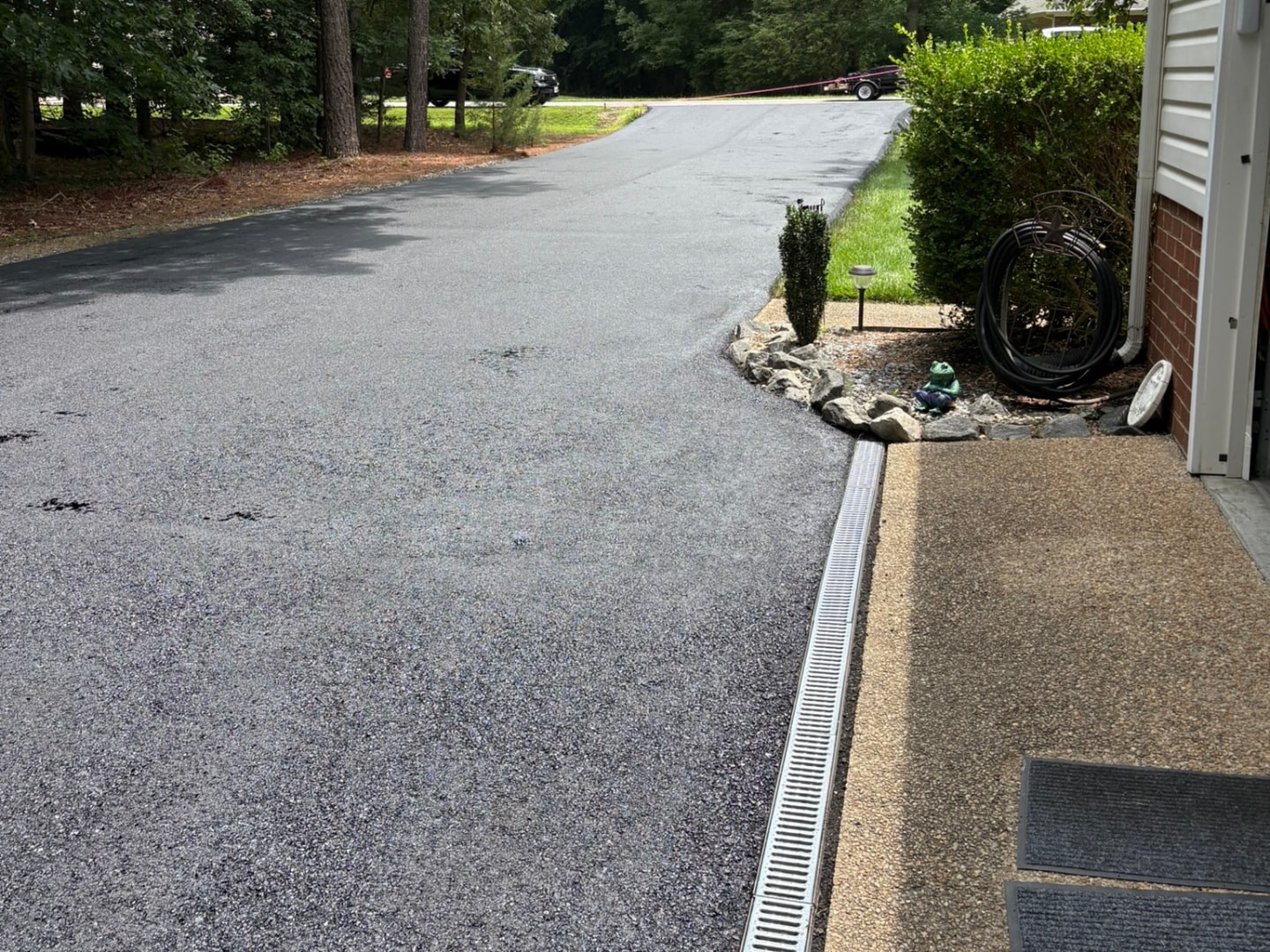 Residential driveway with a trench drain channel running alongside the home to manage water flow