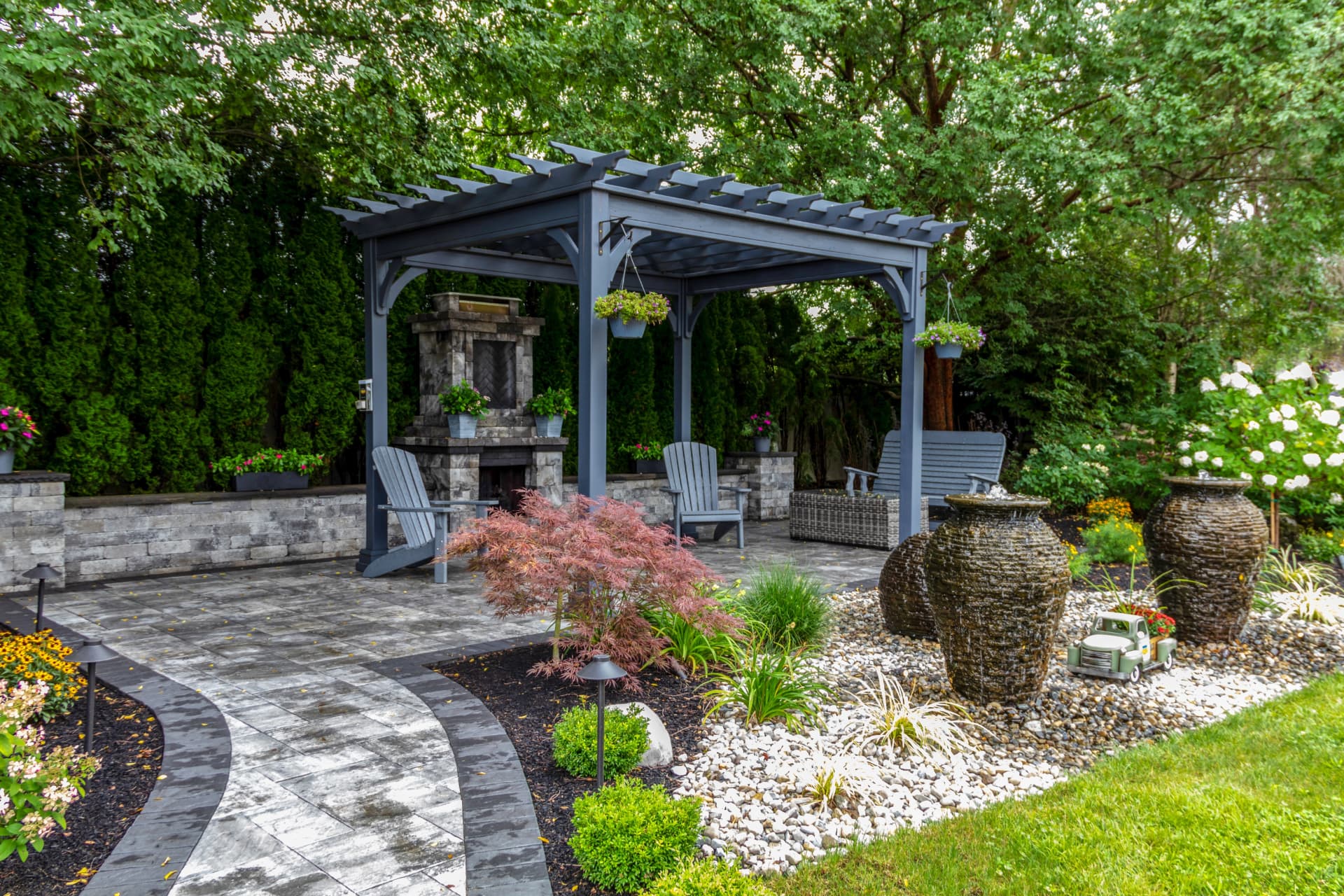 Curved paver walkway connecting a landscaped garden to a pergola seating area