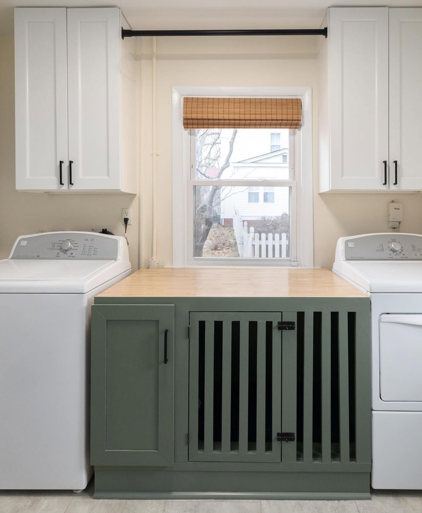 Laundry room with white cabinetry, a folding counter, and a built-in pet crate below