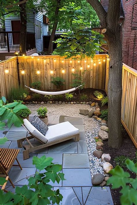 Cozy small backyard with a hammock, string lights, a wooden lounge chair, gravel path, and a wooden fence