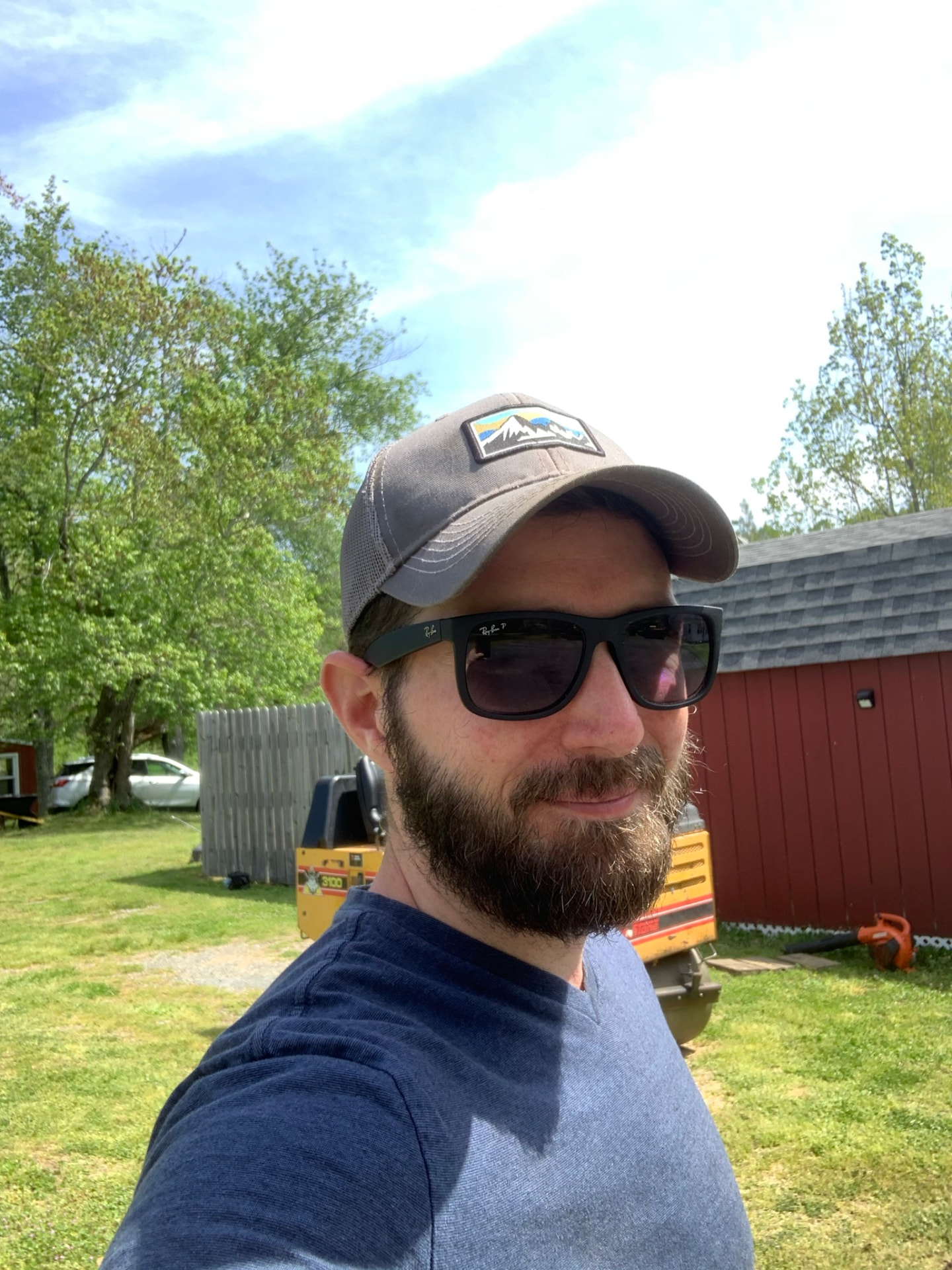 Dave Jordan on a job site, wearing a cap and sunglasses with equipment behind him