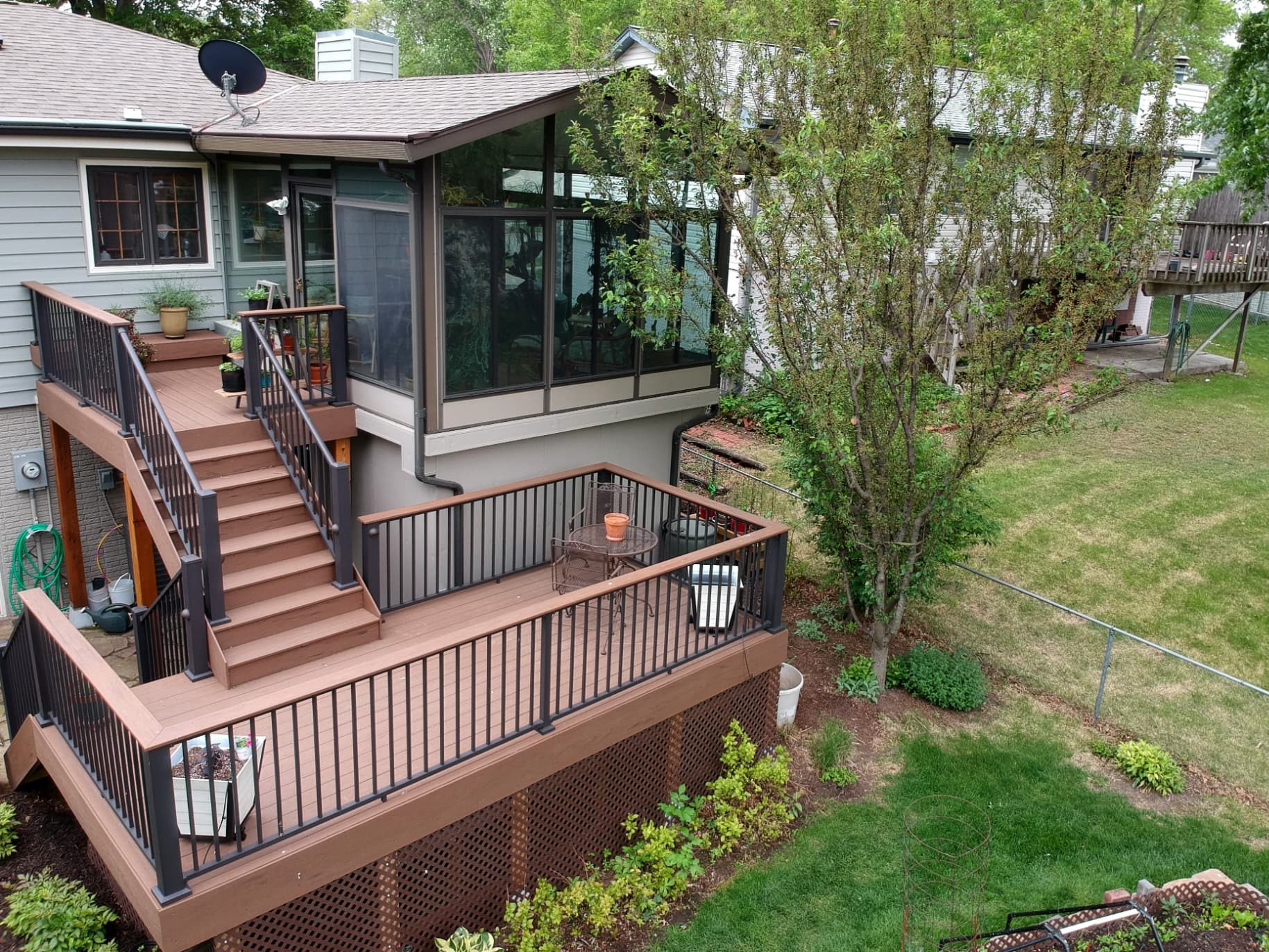 Multi-level deck and screened porch addition on a home with stairs, railings, and backyard views