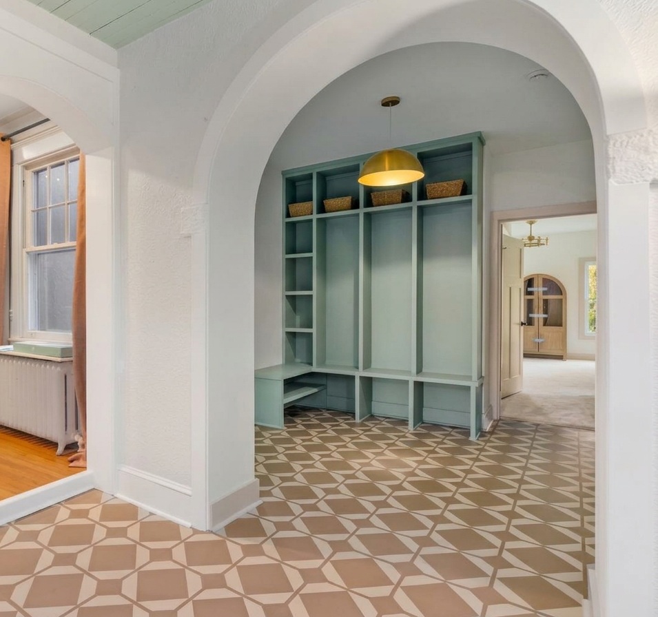 Thoughtfully renovated mudroom with built-in storage, arched openings, and patterned tile flooring